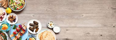 Yaz Akdeniz temalı yemek köşesi sınırı. Fotokopi alanı olan ahşap bir arkaplanda genel görünüm. Izgara şiş, salata, aperatif, pide ve tzatziki..