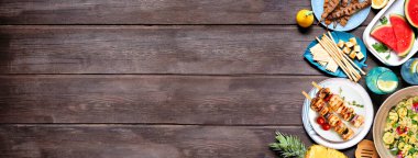 Yaz yemekleri sınırında et şişleri, salata, meyve ve atıştırmalıklar. Koyu ahşap bir arka planda tepeden aşağı manzara. Boşluğu kopyala.