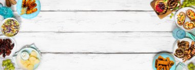 Yaz barbeküsü ya da piknik yemekleri çifte sınır. Hamburger, ızgara et, patates, füme mısır, meyve, salata ve aperatif. Beyaz ahşap bir arkaplanda manzaranın üstünde. Boşluğu kopyala.