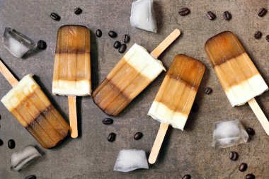 Bir grup kahve ve kremalı dondurma. Kahverengi arkaplana dağılmış üstten aşağı görünüm.