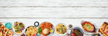 Çeşitli lezzetli yiyeceklerin alt sınırı. Beyaz ahşap bir arka planda tepeden aşağı manzara. Uzayı kopyala Makarna, ekmek, taco, biftek ve restoran temalı yemekler..