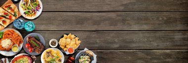 Çeşitli lezzetli yiyeceklerin köşesi. Koyu ahşap bir arkaplanda manzaranın üstünde. Uzayı kopyala Makarna, ekmek, taco, biftek ve restoran temalı yemekler..