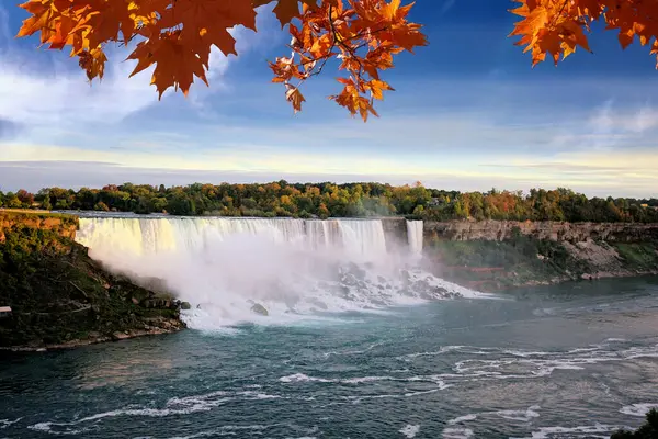 American side of Niagara Falls at dusk with vibrant autumn leaves