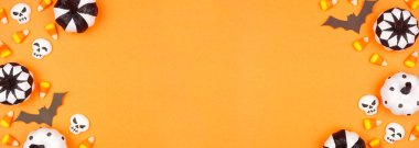 Cadılar Bayramı siyah, beyaz ve turuncu renkli şekerler, yarasalar ve balkabağı dekoru. Fotokopi alanı olan turuncu afiş arkaplanındaki genel görünüm.