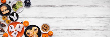 Ürkütücü Cadılar Bayramı kahvaltı köşesi, arka planda beyaz ahşap afiş ve fotokopi alanı. Manzaranın üstünde. Krep, tost, yulaf ezmesi ve meyve çeşitleri..