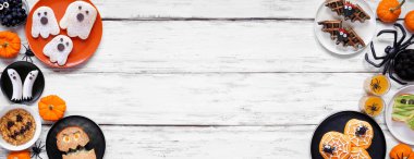 Ürkütücü Cadılar Bayramı kahvaltısı beyaz ahşap kaplamalı arka planda kopya alanı olan çift taraflı sınır. Üst Manzara. Krep, tost, yulaf ezmesi ve meyve.