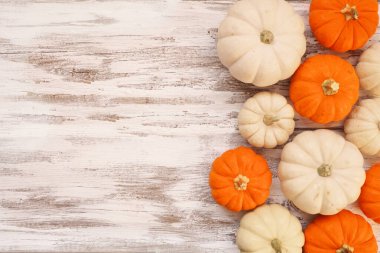 Kırsal beyaz ahşap arka planda turuncu ve beyaz balkabaklarının sonbahar kenarı. Kopyalama alanı ile görünümün üstünde.