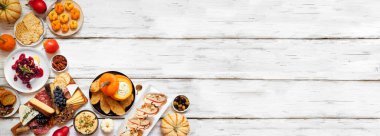 Sonbahar temalı aperatif köşe kenarı beyaz ahşap bir afişe karşı. Şarküteri tahtası, balkabağı ve elma sosu, crostini, peynir ve aperatif. Görünümün üstünde.