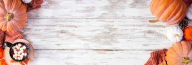 Balkabaklarıyla, kazaklarıyla ve sıcak çikolatayla iç içe. Kırsal beyaz ahşap afiş arkaplanındaki üst görünüm.