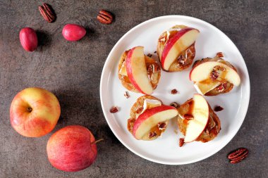 Kırmızı elmalı, peynirli ve cevizli bir tabak crostini aperatifi. Koyu bir arkaplan karşısında en üstteki tablo sahnesi. Parti yemeği konsepti.