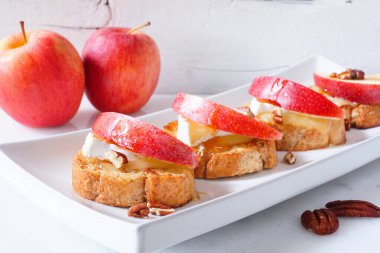 Kırmızı elmalı, peynirli ve cevizli crostini aperatifleri. Beyaz arkaplanlı yan manzara masası sahnesi. Parti yemeği konsepti.