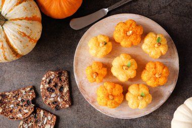 Sonbahar balkabağı peynir topu aperatifleri. Yukarıdan aşağıya masa manzarası, koyu taştan bir arka plan. Sonbahar partisi yemek konsepti.