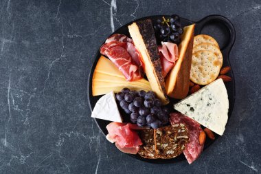 Peynir, et ve aperatiflerden oluşan bir Charcuterie kurulu. Koyu bir arkaplanda genel görünüm.