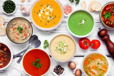 Lezzetli ev yapımı çorba seçimi. Beyaz ahşap arka planda yukarıdan aşağıya doğru görünen masa sahnesi. Sıcak ve samimi yiyecek konsepti.