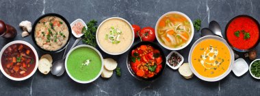 Lezzetli ev yapımı çorba seçimi. Koyu renkli afiş arkaplanındaki tepedeki masa masası sahnesi. Sıcak ve samimi yiyecek konsepti.