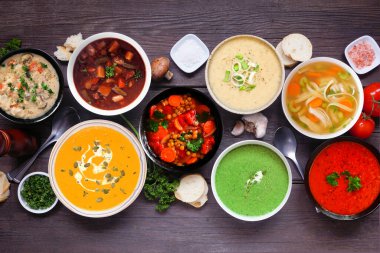 Lezzetli ev yapımı çorba çeşitleri. Koyu renk ahşap arka planda en üstteki masa sahnesi. Sıcak ve samimi yiyecek konsepti.