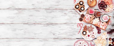 Noel kurabiyeleri ve tatlılar yan sınırda. Beyaz ahşap bir arka planda tepeden aşağı manzara. Kurabiye, turta, çikolata ve sıcak çikolata tepsisi..