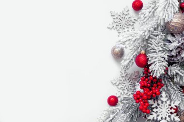 Kırmızı ve altın takılardan, karlı dallardan ve kar tanelerinden oluşan bir Noel kenarı. Beyaz arka planda yukarıdan aşağıya doğru görüş. Boşluğu kopyala.
