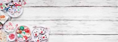 Şirin Noel tatlıları köşedeki köşede. Fotokopi alanı olan beyaz ahşap bir arkaplanda tepeden aşağı manzara. Eğlenceli tatil pişirme konsepti. Kurabiyeler, kekler, çörekler, kekler ve şekerler.