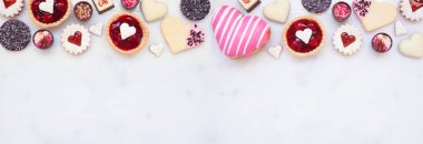 Sevgililer Günü 'nde çeşitli kurabiyeler, çikolatalar ve şekerlerle üst sınır pişiriliyor. Fotokopi alanı olan beyaz mermer bir afiş zemininin üstünde. Aşk ve kalp teması.