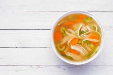 Ev yapımı tavuklu şehriye çorbası, beyaz ahşap arka planda manzarası.