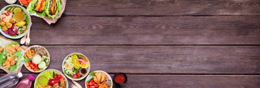 Sağlıklı bir şekilde fast food köşesi sınırına gidin. Koyu renk ahşap bir arkaplan üzerinden genel manzara. Marullu fasulye burgerleri, besleyici kaseler ve marul ambalajlı masa sahnesi. Boşluğu kopyala.