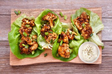 Ballı, sarımsaklı ve karnabahar ızgaralı sağlıklı marul. Kırsal ahşap arka planda üst manzara. Bitki temelli diyet konsepti.