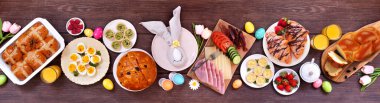 Paskalya kahvaltısı ya da brunch masası sahnesi. Koyu ahşap bir arkaplanda manzaranın üstünde. Ekmek, kiş ve çeşitli bahar yemekleri..