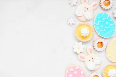 Paskalya ya da bahar temalı, çeşitli kurabiyeler ve tatlı tatlılarla sınırda pişiyor. Kopya alanı olan beyaz mermer bir arkaplan üzerinde genel görünüm.