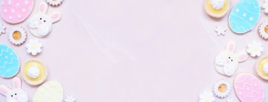 Paskalya ya da bahar temalı çift taraflı pişirme çeşitli kurabiyeler ve tatlı tatlılar. Fotokopi alanı olan pembe taştan bir arkaplanda üstten aşağı görünüm.