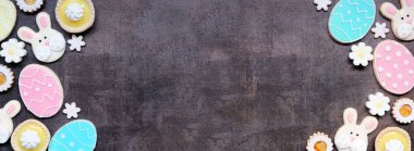 Paskalya ya da bahar temalı çift taraflı pişirme çeşitli kurabiyeler ve tatlı tatlılar. Fotokopi alanı olan karanlık bir taş afiş zemininde görünümün üzerinde.