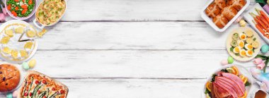 Geleneksel Paskalya jambonu yemeği. Beyaz ahşap kaplamalı arka planda kopya alanı olan çift kenarlı bir görünüm üzerinde. Jambon, istiridyeli patates, sebze tabağı, yumurta, ekmek ve limonlu tatlı..