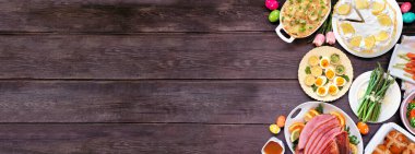 Geleneksel Paskalya jambonu yemeği. Üst görünüm kenarı koyu ahşap afiş zemininde fotokopi alanı var. Jambon, istiridyeli patates, sebze tabağı, yumurta, ekmek ve limonlu tatlı..