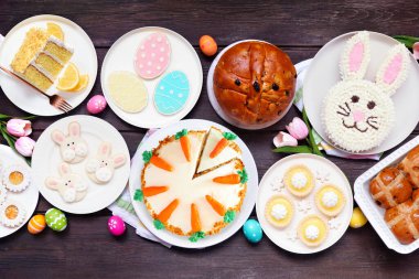 Paskalya ya da bahar tatlı masası sahnesi. Koyu bir ahşap arka planda manzaranın üstünde. Tavşan keki, renkli kurabiyeler, ekmekler, turtalar ve çeşitli tatlılar..