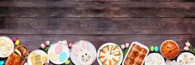 Paskalya ya da bahar tatlıları alt sınır. Koyu ahşap bir arka planda tepeden aşağı manzara. Tavşan keki, renkli kurabiyeler, ekmekler, turtalar ve çeşitli tatlılar. Boşluğu kopyala.