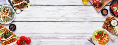 Sağlıklı bitki temelli vejetaryen gıda çifte sınırı. Beyaz ahşap bir arka planda. Jackfruit burger, mantarlı taco, karpuz ve karnabahar bifteği, havuç sosisi, cevizli bolonez