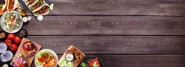 Sağlıklı bitki temelli vejetaryen gıda sınırı. Koyu ahşap arka planda üst manzara. Jackfruit burger, mantarlı taco, karpuz ve karnabahar bifteği, havuç sosisi, cevizli bolonez
