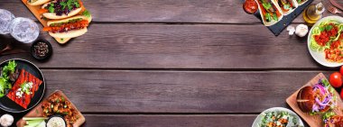 Sağlıklı bitki temelli vejetaryen gıda çifte sınırı. Ahşap kaplamalı bir arka planda. Jackfruit burger, mantarlı taco, karpuz ve karnabahar bifteği, havuç sosisi, cevizli bolonez