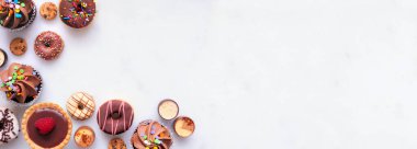 Tatlılarla dolu bir tatlı köşesi kenarı. Fotokopi alanı olan beyaz taş afiş arkaplanındaki üst görünüm.