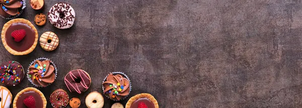 Tatlı köşesinde çeşitli tatlılar var. Fotokopi alanı olan koyu taştan bir arkaplan üzerindeki en üst görünüm.