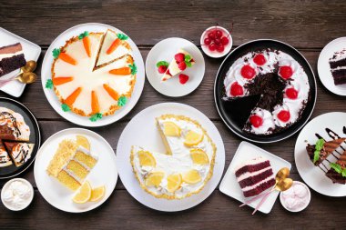 Pasta çeşitleriyle tatlı masası sahnesi. Koyu renk ahşap arka planda üst manzara. Kara orman, limon, havuç, kırmızı kadife, çikolata ve peynirli kek..