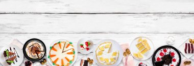 Çeşit çeşit pastalarla tatlandırılmış alt sınır. Beyaz ahşap bir arka planda yukarıdan aşağıya doğru görünüyor. Uzayı kopyala Kara orman, limon, havuç, kırmızı kadife, çikolata ve peynirli kek..