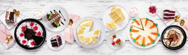 Çeşitli pastalarla tatlı masası sahnesi. Beyaz ahşap bir arkaplanda manzaranın üstünde. Kara orman, limon, havuç, kırmızı kadife, çikolata ve peynirli kek..