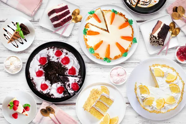 Çeşitli pastalarla tatlı masası sahnesi. Beyaz ahşap arka planda yukarıdan aşağıya doğru. Kara orman, limon, havuç, kırmızı kadife, çikolata ve peynirli kek..