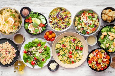 Lezzetli ev yapımı salata çeşitleri. Beyaz ahşap arka planda en iyi masa manzarası. Yaz yemekleri konsepti. Patates, sezar, makarna ve yeşil salata..
