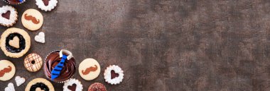 Babalar Günü temalı fırın köşesi sınırı çeşitli kurabiyeler ve tatlı ikramlarla. Fotokopi alanı olan karanlık bir taş afiş zemininde görünümün üzerinde.