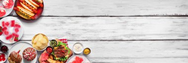 Kanada Vatanseverlik Günü yemeği. Beyaz ahşap bir arka planda, köşedeki kenar tarafında. Sosisli sandviç, hamburger ve akçaağaç yaprağı kırmızı ve beyaz temalı atıştırmalıklar. Boşluğu kopyala.