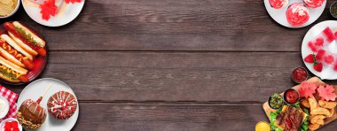 Kanada Vatanseverlik Günü yemeği. Koyu renk ahşap bir arka planda çift kenar manzaralı. Sosisli sandviç, hamburger ve akçaağaç yaprağı kırmızı ve beyaz temalı atıştırmalıklar. Boşluğu kopyala.