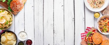 Hamburgerler, klasik salatalar ve abur cuburlarla barbekü. Beyaz ahşap bir arkaplandan yukarıdaki masa manzarası. Boşluğu kopyala.