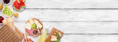 Yaz pikniği köşe sınırı. Beyaz ahşap bir arka plan üzerinde üst görünüm. Piknik sepeti, meyve, salata, sandviç ve atıştırmalıklar. Boşluğu kopyala.